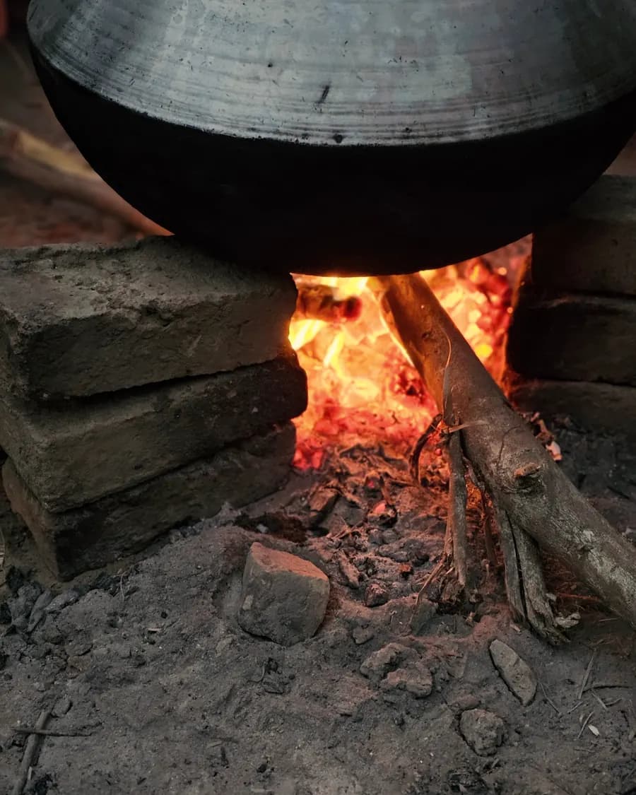 A pot hanging low over a wood fire